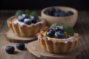 Shortbread baskets with curd cream, apricot and blueberry berries on a wooden mat