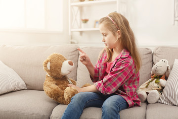 Little girl playing with teddy bear at home