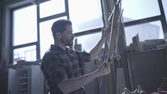 Handsome man in his fourties working with wood in his workshop