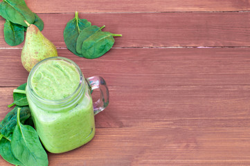 Fresh green detox smoothie, spinach, pear, on a brown wooden background (copy space)