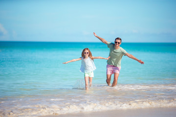 Family at tropical beach walking together on tropical Carlisle bay beach with white sand and turquoise ocean water at Antigua island in Caribbean.