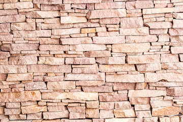 textured background made of light red stones wall