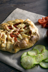 freshly baked Galeta with vegetables and cheese on a wooden table with ingredients, olive oil, red pepper, tomatoes and raw dough