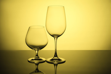 Two glass glasses on a yellow background.
