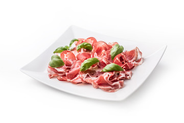 Prosciutto. Curled slices of delicious Italian Prosciutto with basil