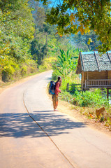 girl traveler walking along the road with a backpack