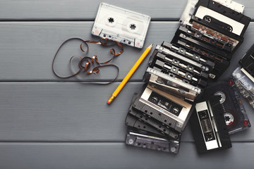 Vintage cassettes and pencil to rewind tape on gray wooden background