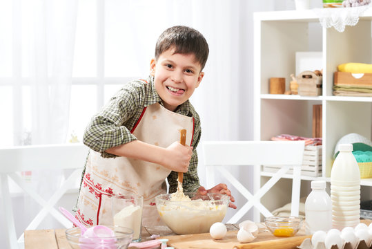 Boy cooking at home, making dough, buns and cookies