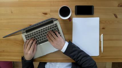 Overhead of a man at his desk with a cup of coffee