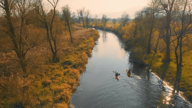 Aerial wide shot of two kayaks going up the river in in amazing landscape on a beautiful autumn sunny day.
