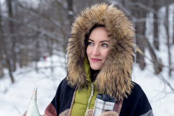 Close-up of a woman traveling in winter clothes standing in the winter forest with a map foggy in the morning. Wanderlust. copy space