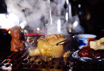 Clay three-toed tea toad with a coin in his mouth on the background of a tea table. Tea ceremony