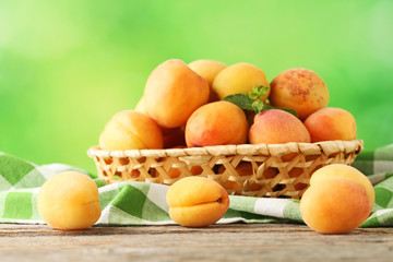 Sweet apricots in basket on grey wooden table