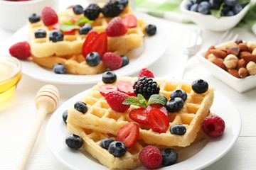 Sweet waffle with berries on white wooden table