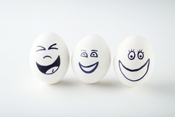 Eggs with funny faces on white background