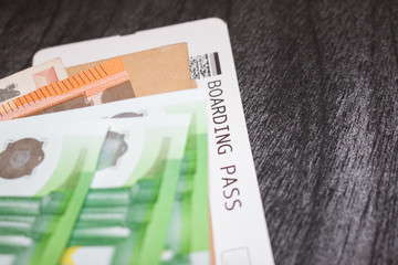 Airline tickets and money on the table. Euro banknotes and Boarding pass. The concept of buying the ticket for travel. Grey Copy paste background. Concept for trip on the background of a wooden table