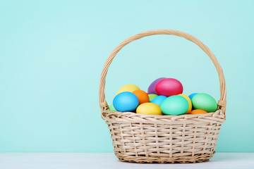 Colorful easter eggs in basket on mint background