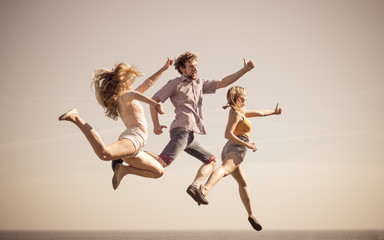 Carefree friends jumping by sea ocean.