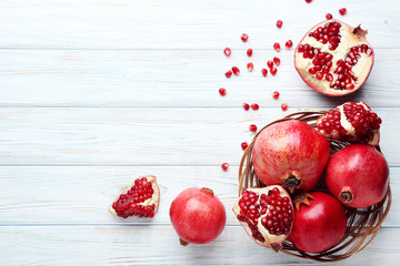 Ripe and juicy pomegranate in basket on wooden table