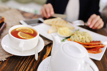 tea with lemon on the background of breakfast, burlap, old books, mobile phone and wooden table