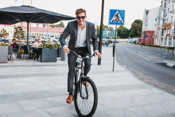 Fototapeta premium Businessman riding bicycle to work on urban street in morning.