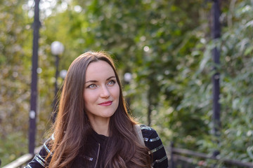 Frontal portrait of a long-haired brunette in an autumn city Park