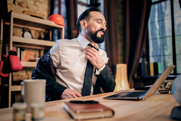 Businessman having relaxing talk on Skype with friend,.Untie his shirt.