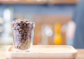 Coffee beans in a cup grass on the wooden table