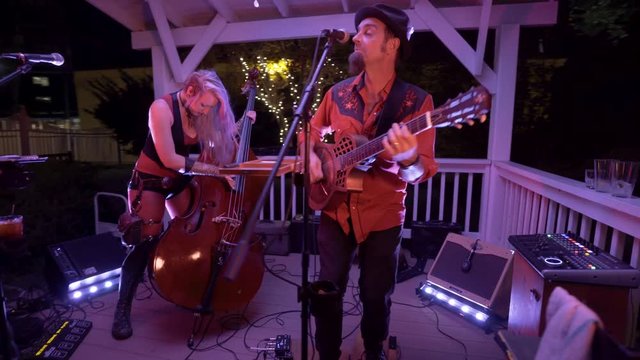 Male guitarist and female stand-up bass player rock to the music as the camera glides past them.
