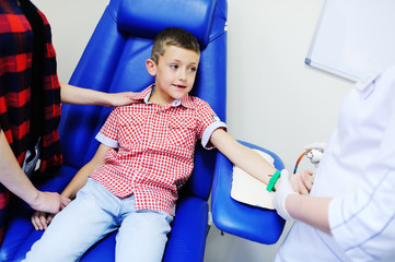 a doctor or nurse takes blood from a vein in a child of a boy. Blood chemistry