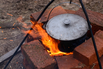 Fish soup boils in a cauldron on an open fire. Soup in a pot on a fire, picnic in nature