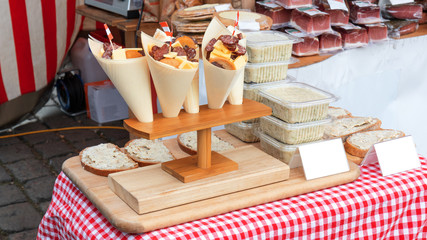 the snack, variation of cheese and sausages in the paper cone at street food farmers market. Bread...