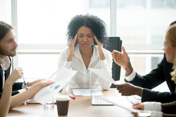 Stressed overwhelmed african businesswoman feels tired at corporate meeting, exhausted black female...