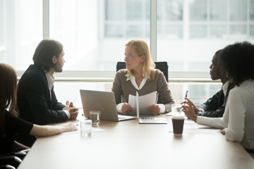 Woman boss discussing new project or financial report at group briefing with diverse employees,...