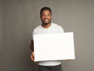 Picture of young african-american man holding white blank board