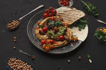 Hummus with vegetables and seafood on black background