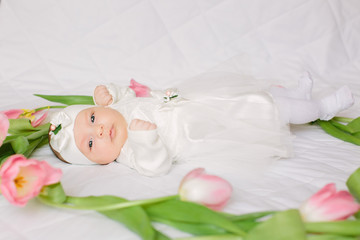 Obraz na płótnie Canvas Little beautiful newborn girl lying on the bed among the flowers
