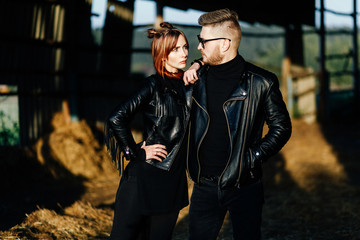 stylish glamorous couple in black leather jackets posing in a hangar