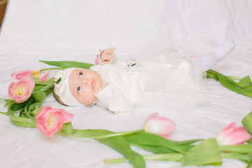 Fototapeta na wymiar Little beautiful newborn girl lying on the bed among the flowers