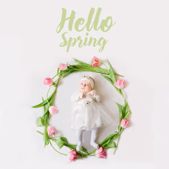 Little beautiful newborn girl lying on the bed among the flowers and the inscription Hello Spring