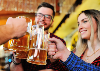 Friends clink glasses of beer glasses close-up on the background of the pub