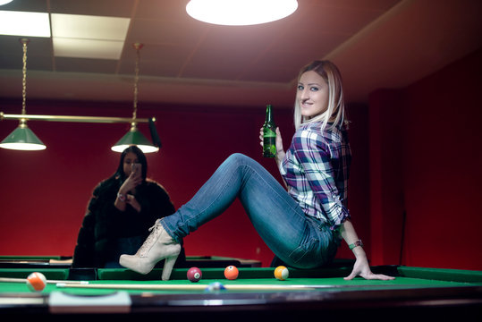 Attractive blond is sitting on billiard table