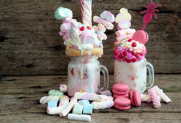 crazy shake. Freakshake from pink smoothie, cream with marshmallos, macarons and colorful candies