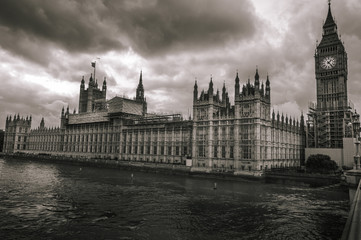 Obraz premium A river side view of dark and cloudy skies hovering above Big Ben and Parliament in London. 