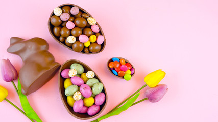 Happy Easter overhead with chocolate Easter eggs and decorations on a wood table background