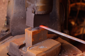 hands of a blacksmith with a tool on the background of a forge close-up