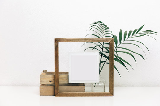 Mock up wooden frame with green tropical leaves. Nordic decorations, Scandinavian interior