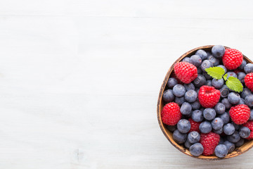 Juicy and fresh blueberries with green mint on rustic blue table.