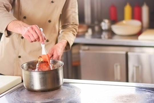 Chef processing lamb shank in saucepan. The process of cooking shank of lamb at professional kitchen of european restaurant.