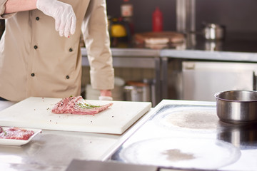 Chef processing ribs with spices. Cropped image of chef cooking lamb ribs at european restaurant.